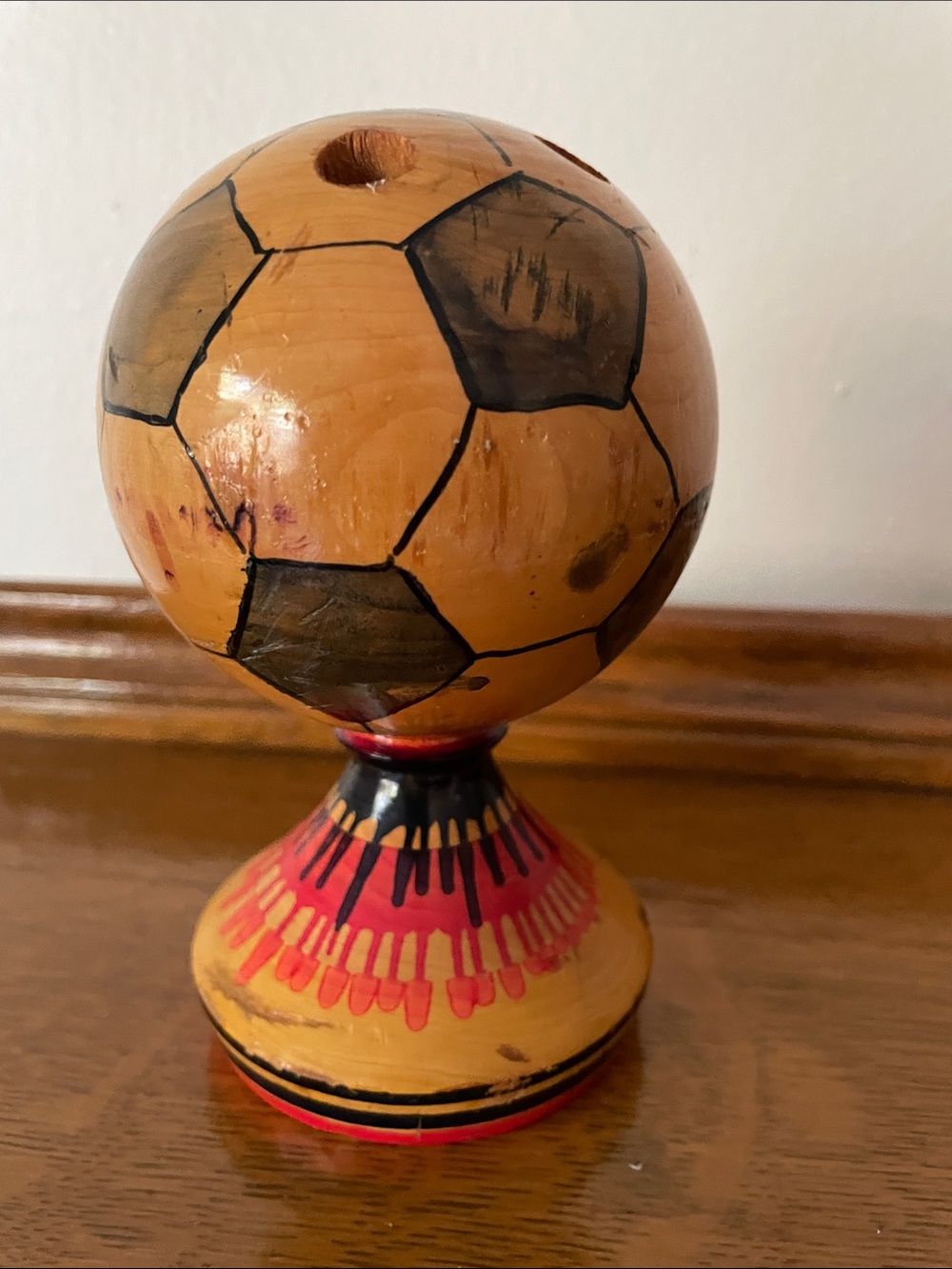 A mid-century handmade wooden soccer ball pencil holder on a pedestal.